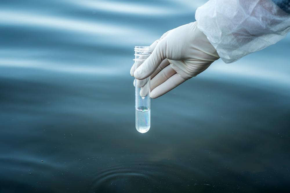 Examination of water quality in a natural reservoir. a test tube in a man's hand with water to check its purity.